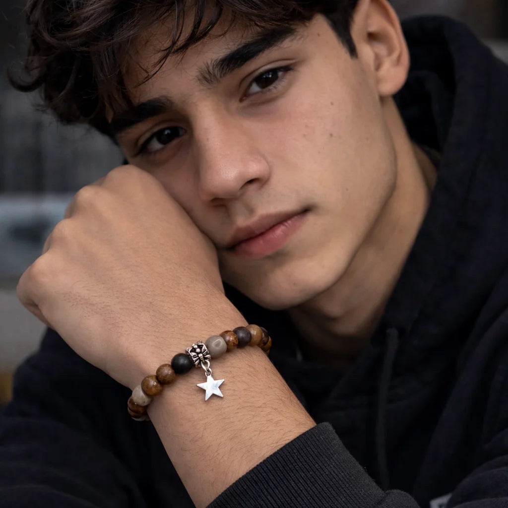 Person wearing a bracelet with star charm and other beads, against a blurred background