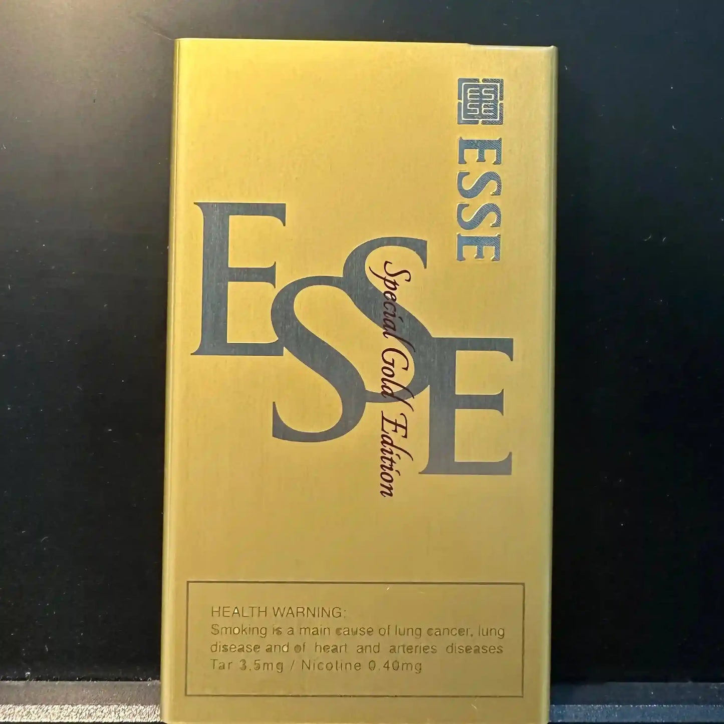 Esse Special Gold Edition cigarette pack held by a hand with a dark background