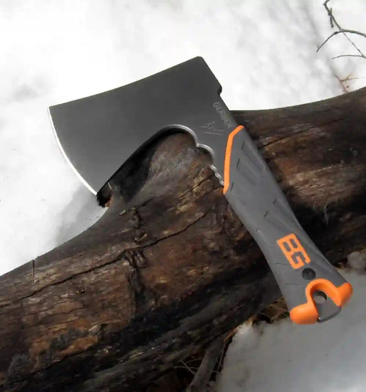 Axes with orange handles on a log against a snowy background