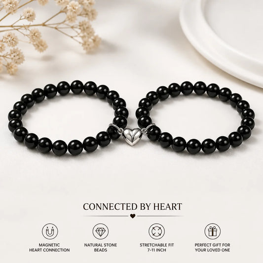 Two black beaded bracelets with a silver heart charm on a white background.