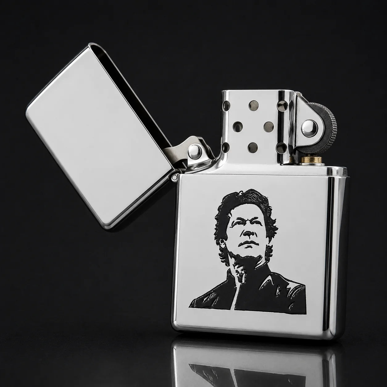 A polished silver metal lighter with its lid open, featuring a black-and-white portrait engraving on the front. The lighter is photographed on a dark reflective surface against a black background.
