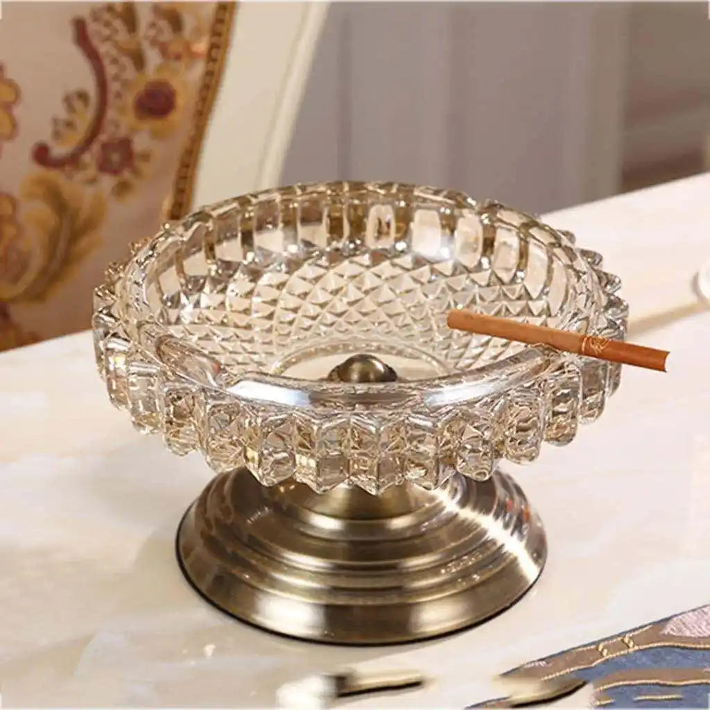 Clear glass ashtray with a metal base on a table
