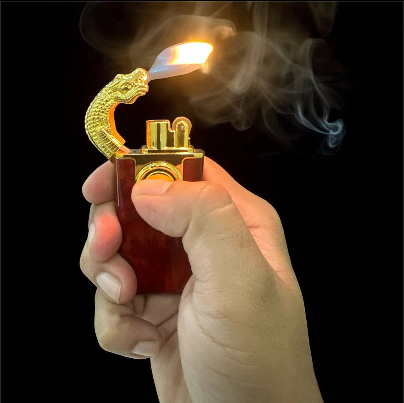 Hand holding a dragon-themed lighter with flame and smoke against a black background