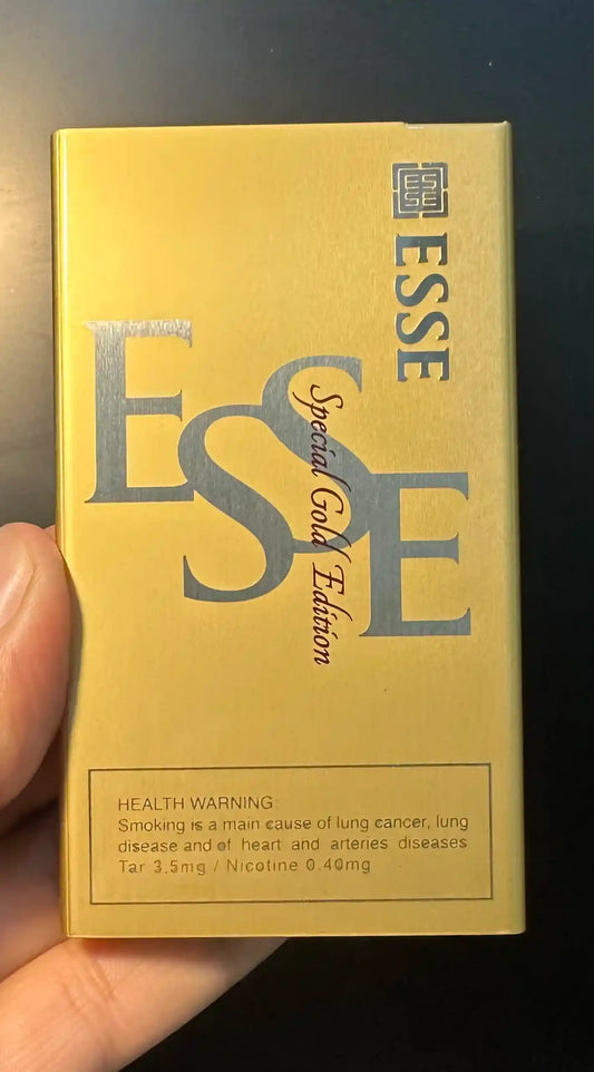 Esse Special Gold Edition cigarette pack held by a hand with a dark background