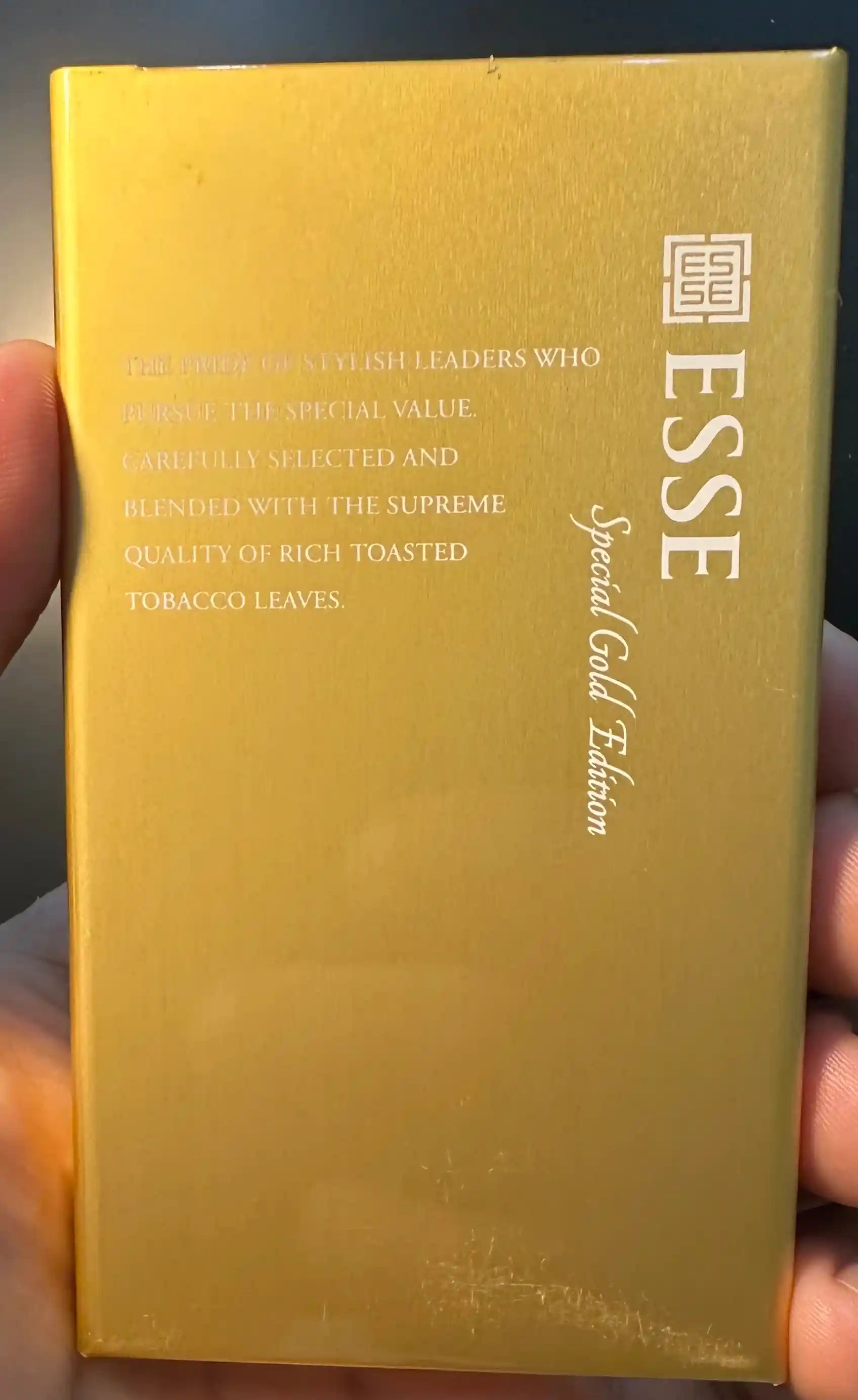 Esse Special Gold Edition cigarette pack held by a hand with a dark background