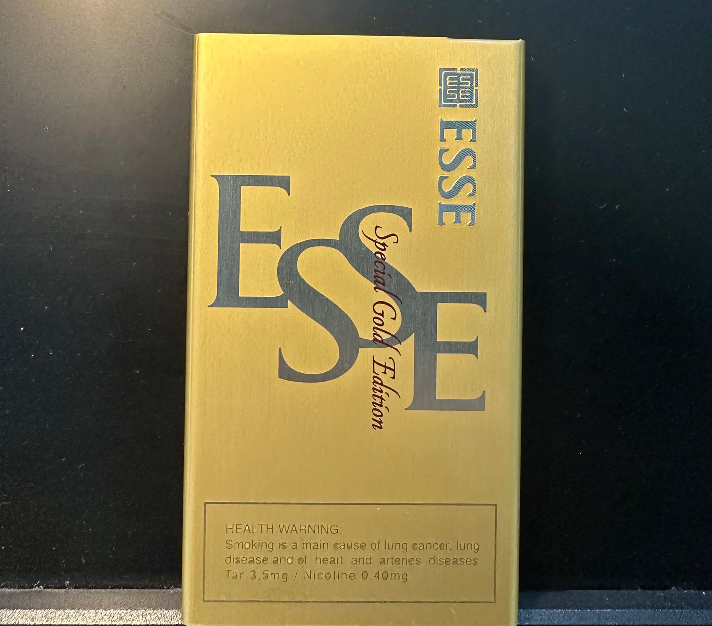 Gold packaging of ESSE with text and logo on a black background