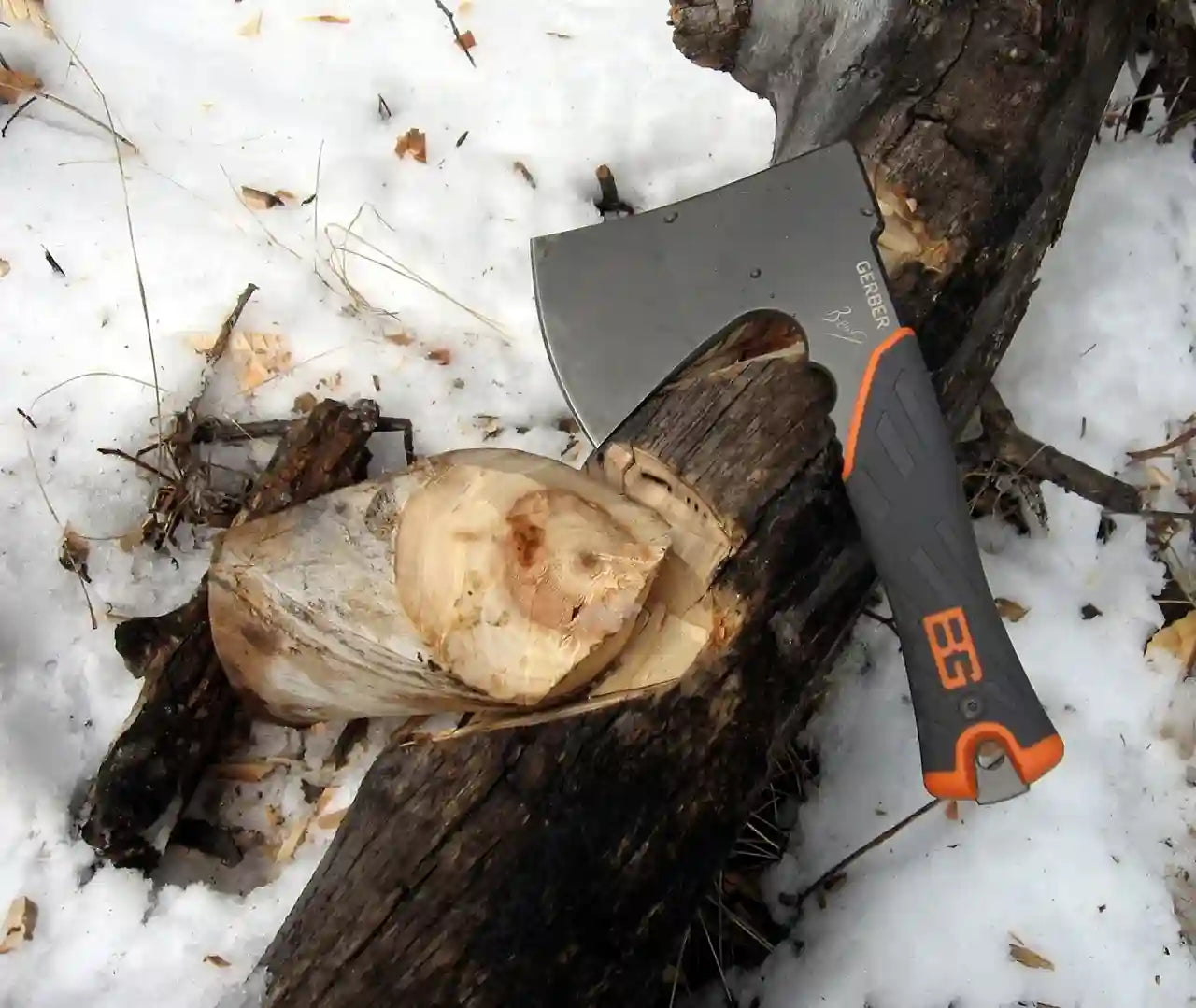 Felling axe with orange handle on a log in the snow