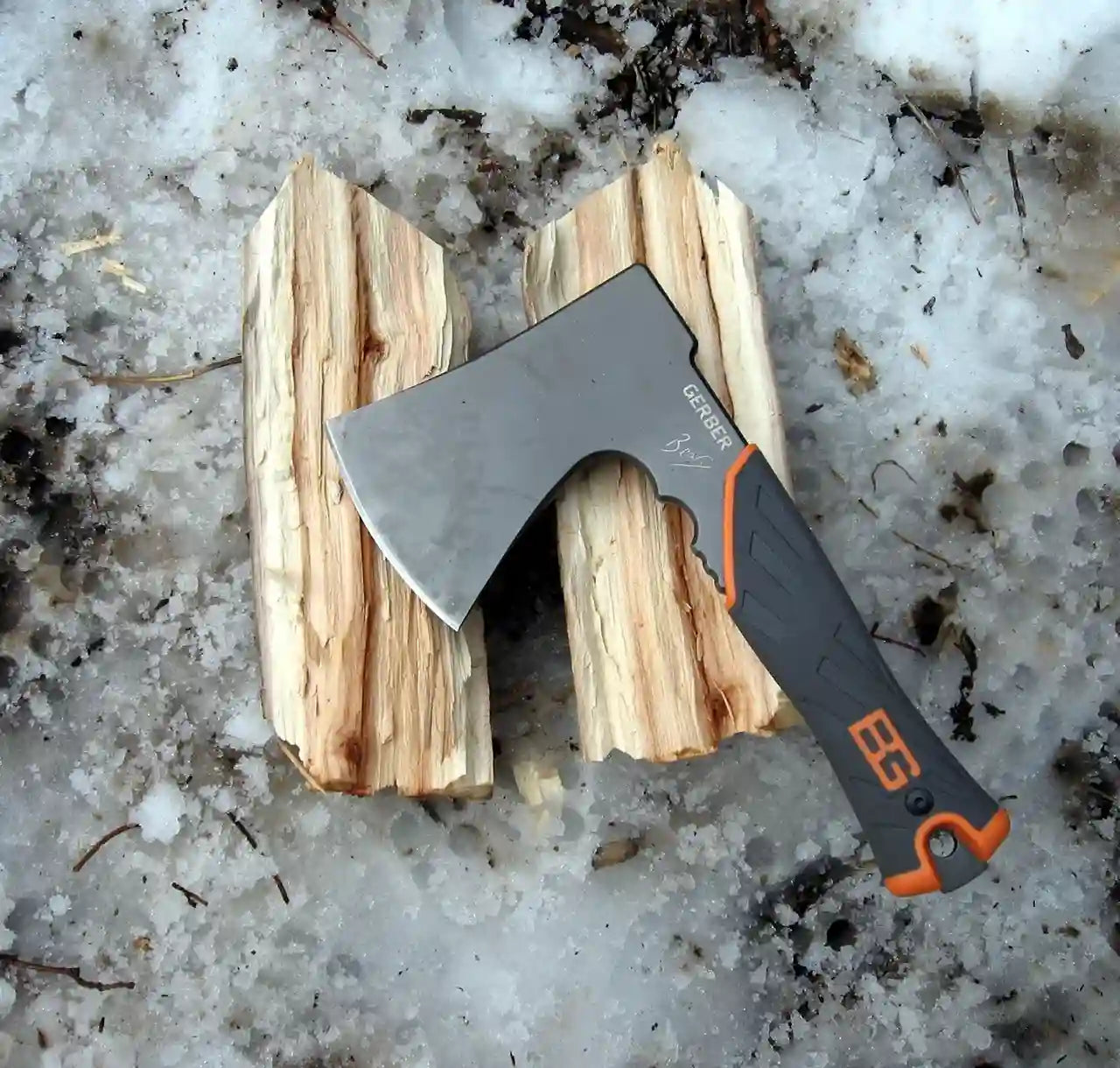Axes with orange handles on a piece of wood, set against a snowy ground.