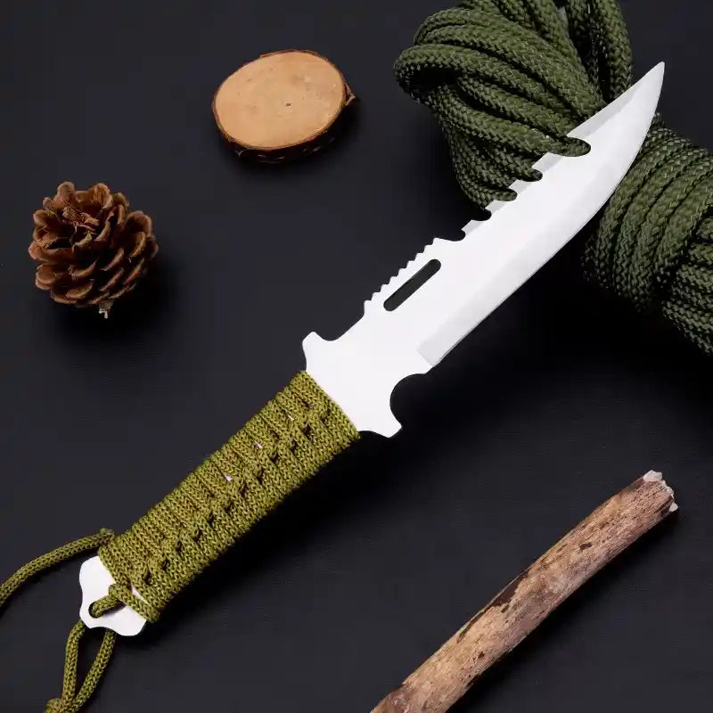 Knife with green handle and cord, pine cone, and stick on a dark background