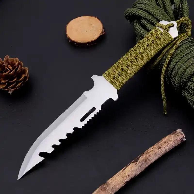 Knife with a green handle on a dark surface with natural elements