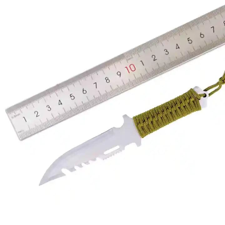 Knife with a green paracord handle next to a ruler on a white background