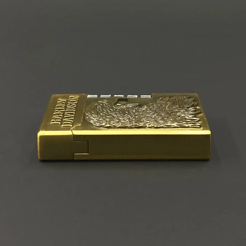 A gold-colored metal lighter featuring an embossed eagle design set against a dark gray background.