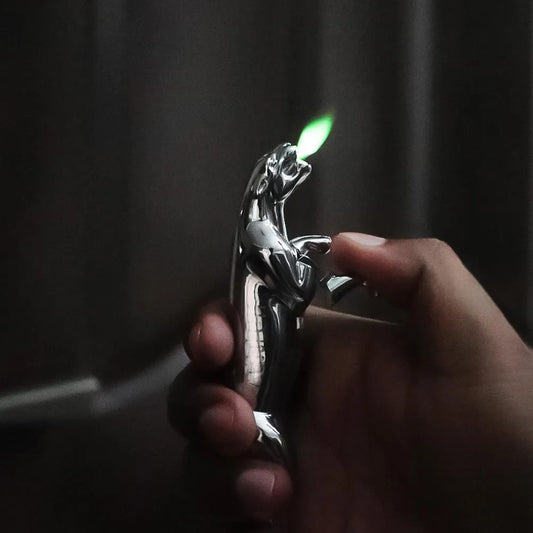 Hand holding a jaguar Lighter with a lit flame against a dark background