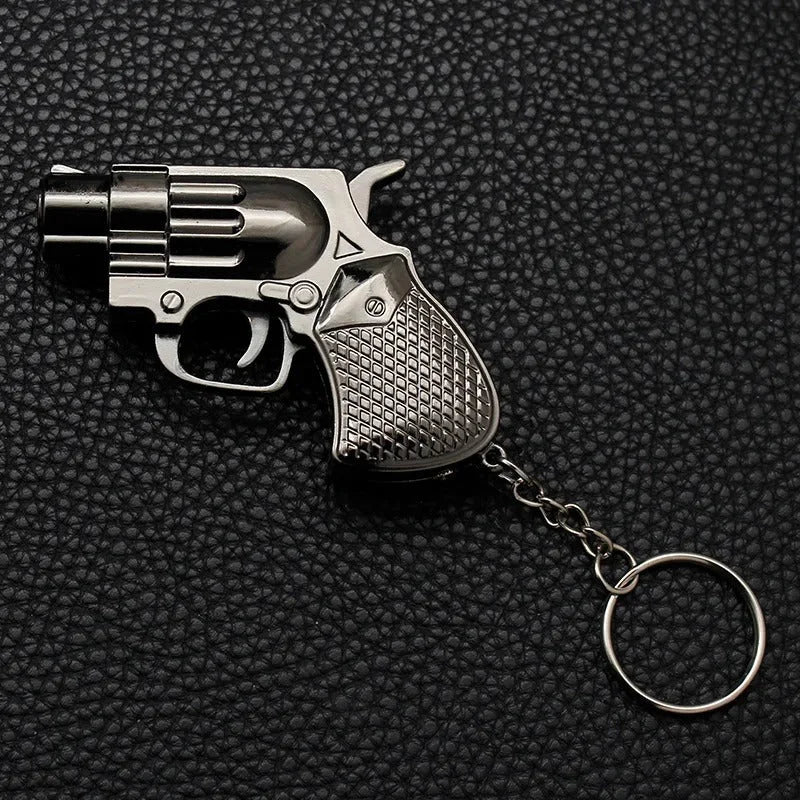 Metallic revolver-shaped Lighter with keychains on a black textured background