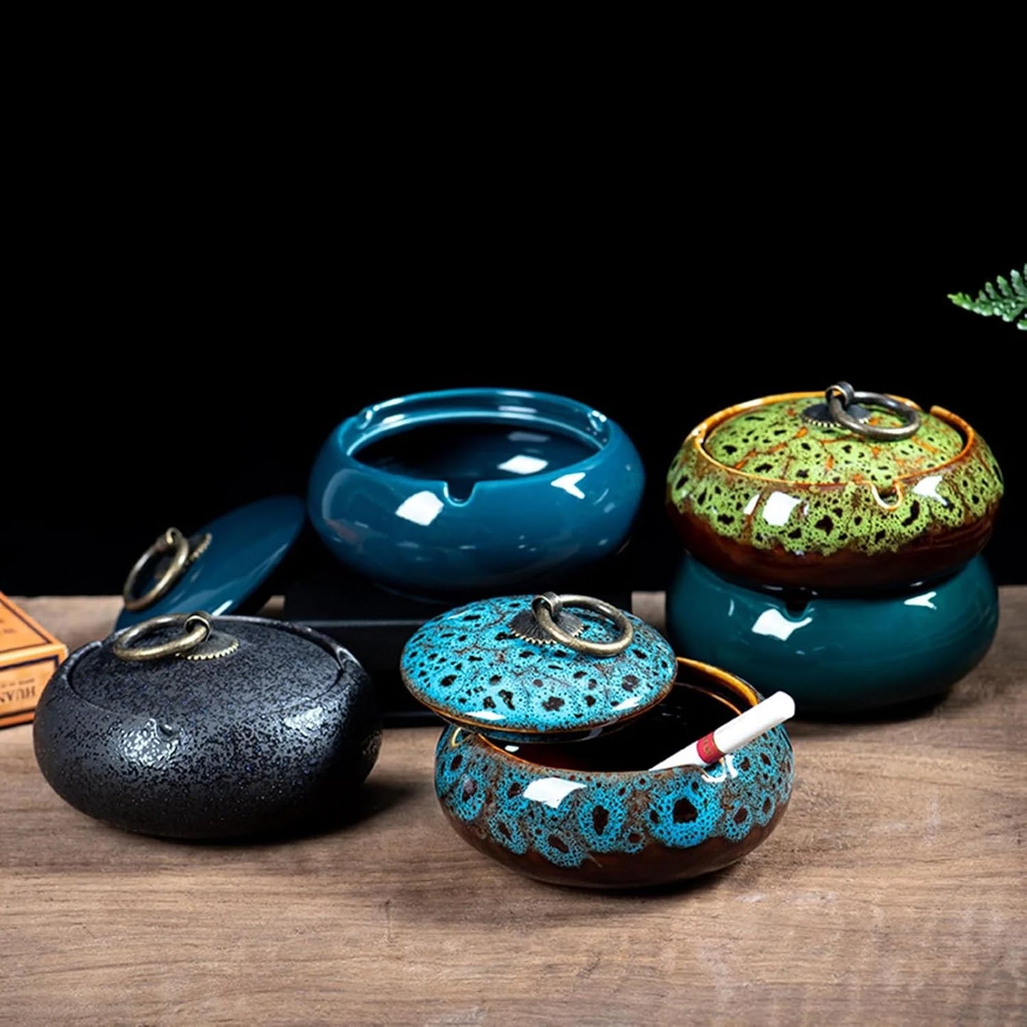 Set of ceramic ashtrays with decorative lids on a wooden surface