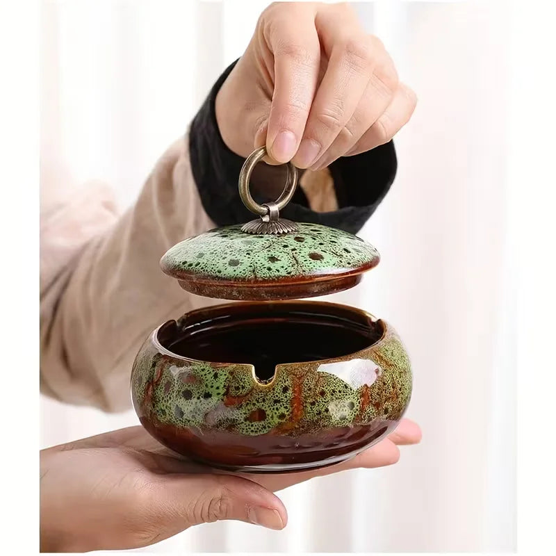 Person holding a ceramic Ashtray with a green lid against a white background
