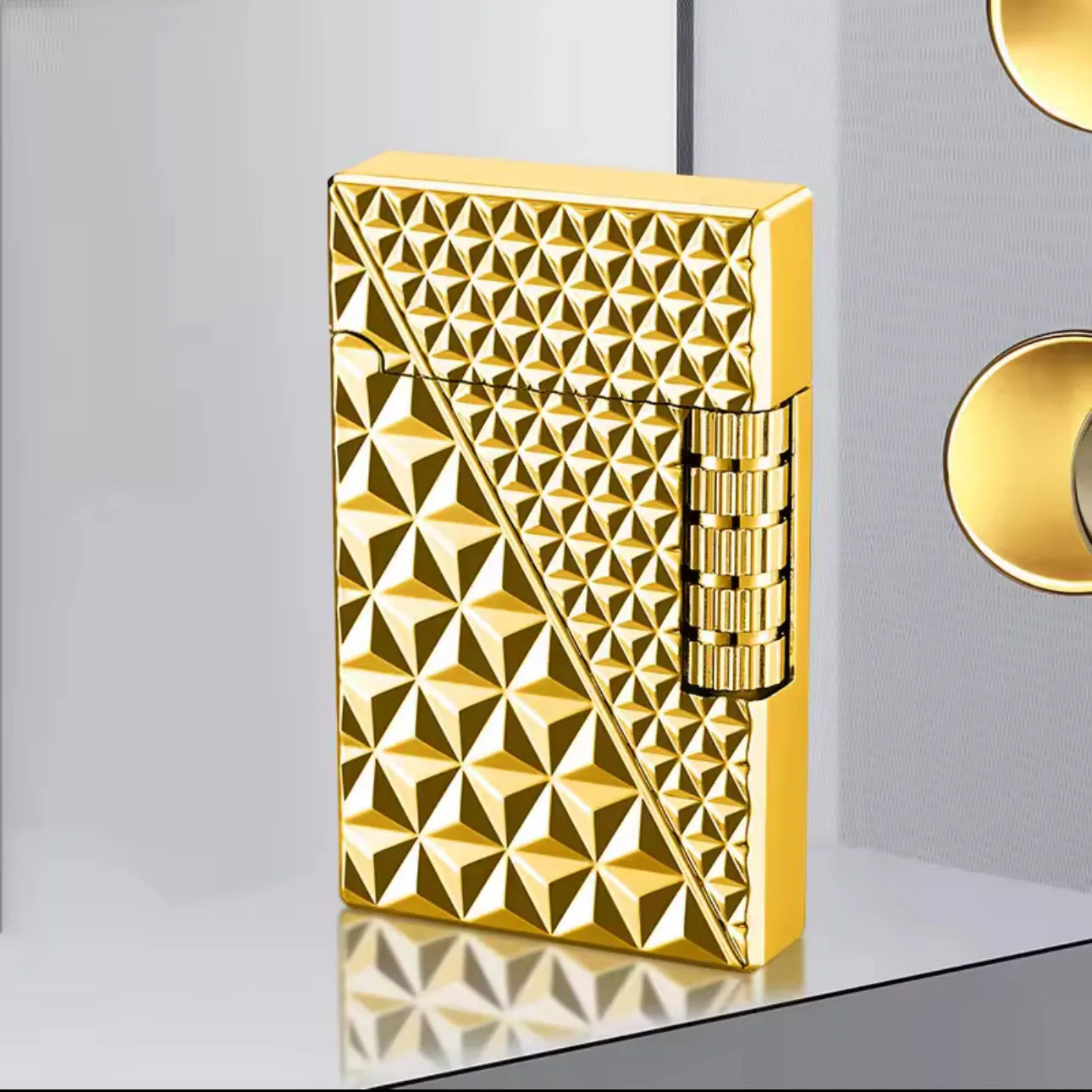 Gold lighter with geometric pattern on a reflective surface