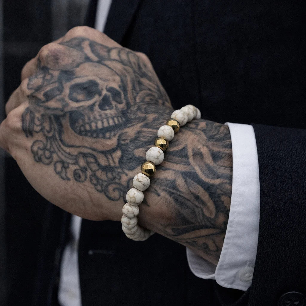 Person wearing a bracelet with skull tattoo on arm
