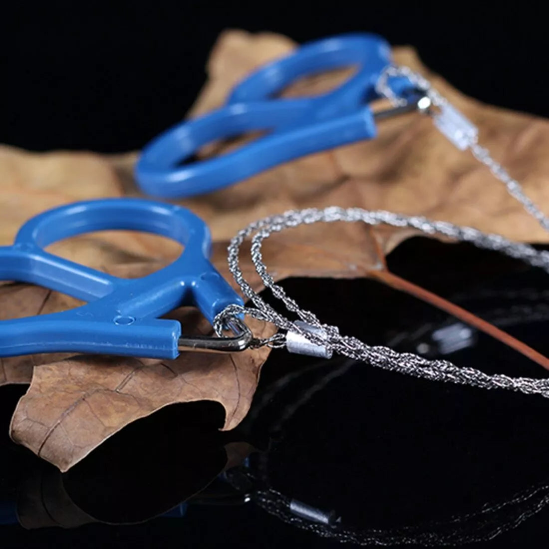 Blue and silver wire saw on a dark background with leaves