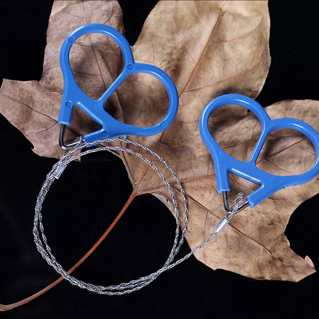 Blue and silver wire saw on a dark background with leaves