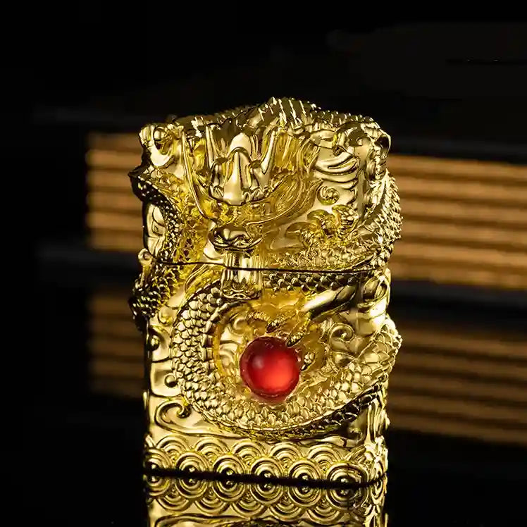 Gold lighters with dragon design and red gemstone on a dark background
