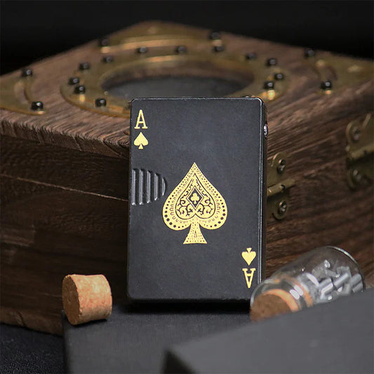 Black playing card lighter with gold spade symbol on a wooden surface