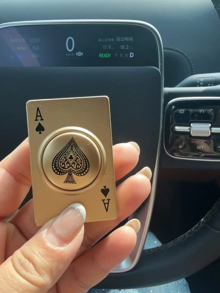 Gold playing card lighter with ace of spades held in front of a car's digital display.