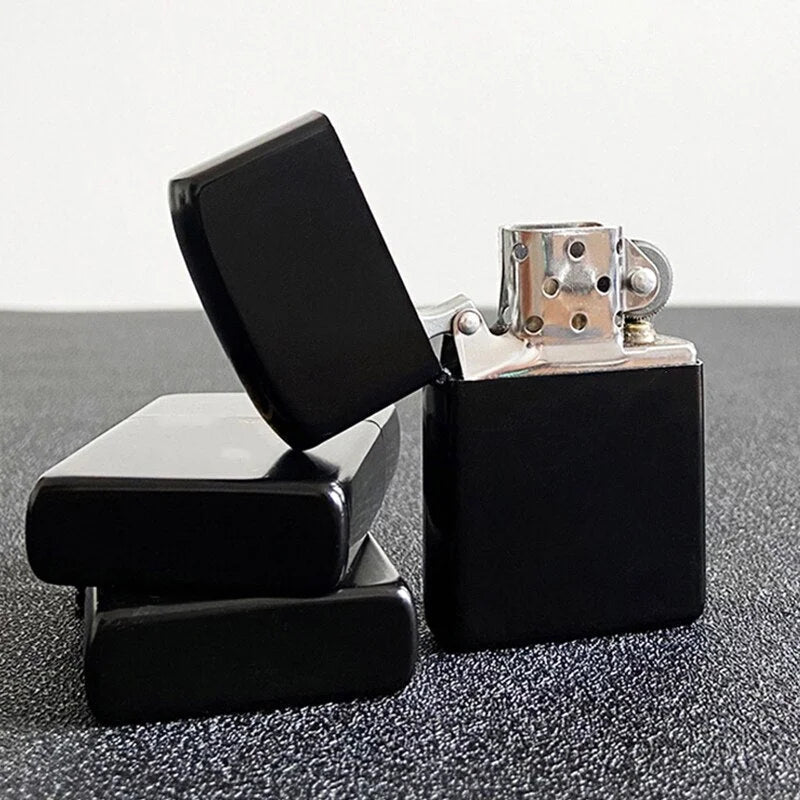 Black Zippo lighter with open lid on a gray surface